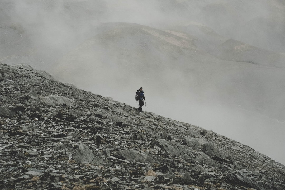 A man climbing down a rugged mountain terrain, symbolizing the difficult journey of discipleship