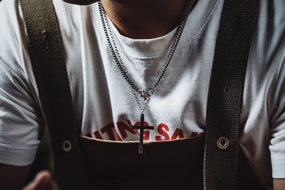 Masculine Christian man wearing a cross necklace and suspenders, symbolizing faith expressed through everyday clothing