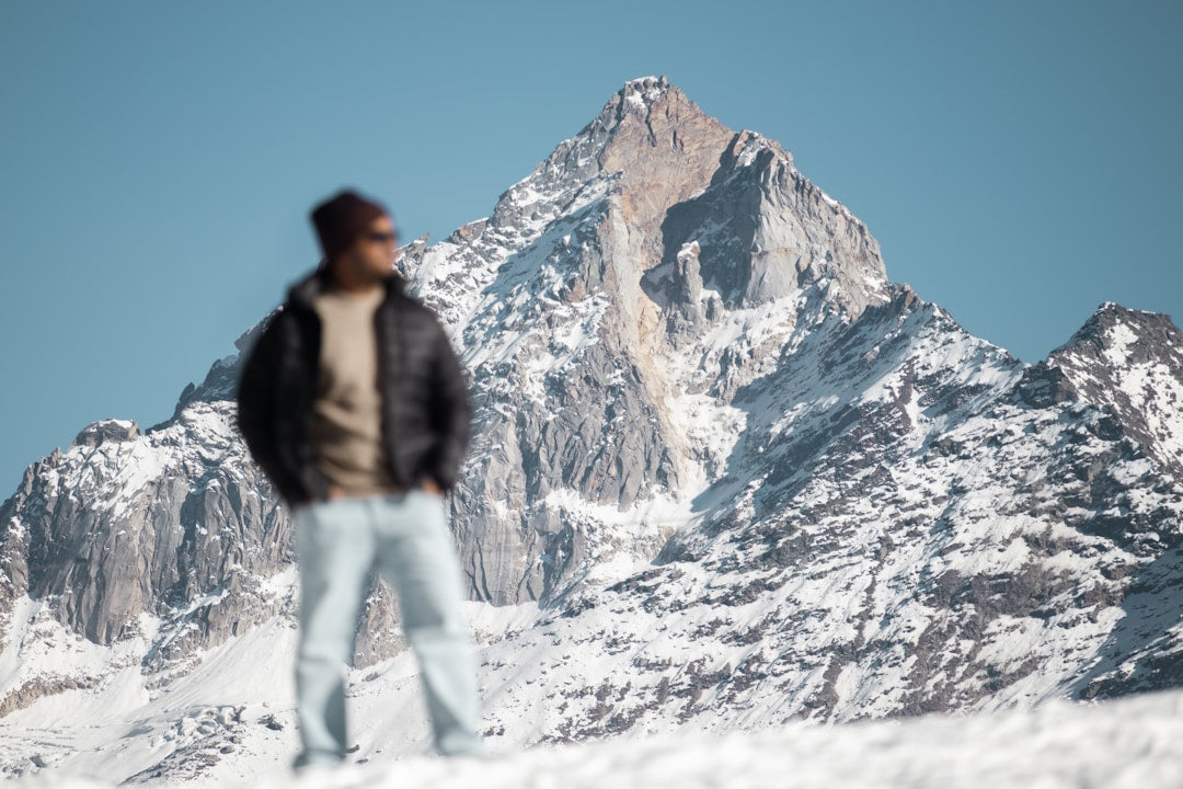 Man standing on a snowy mountain peak looking out over a dramatic landscape, representing courage and strength.