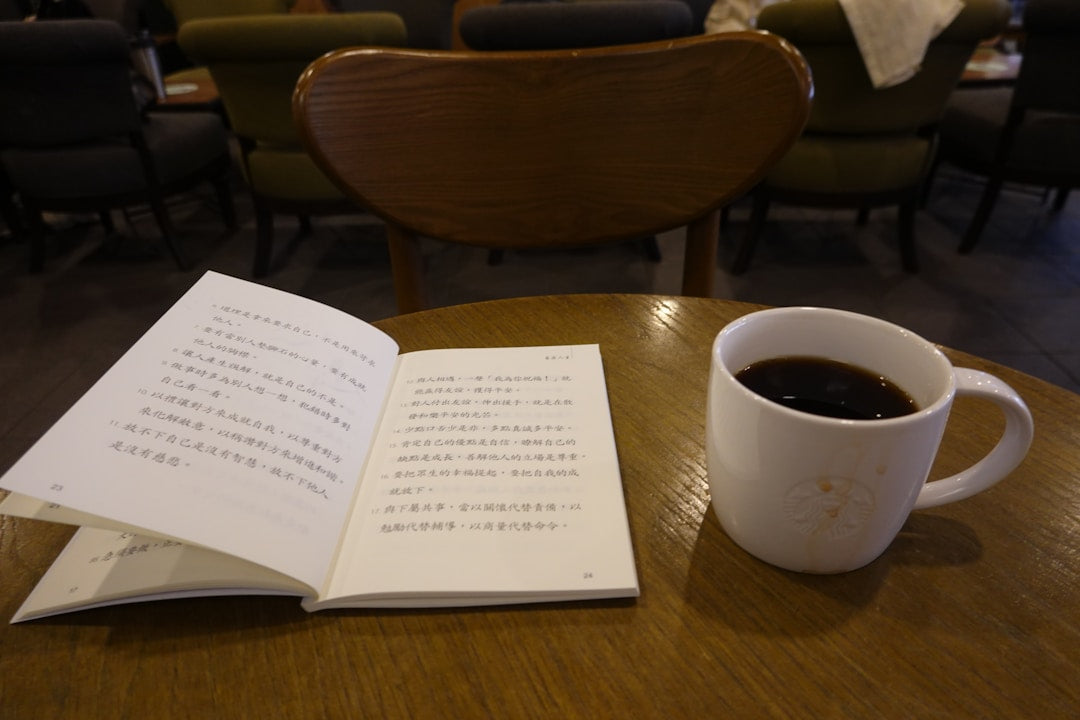 A mug of coffee sitting next to an open Bible on a wooden table, representing men's discipleship.